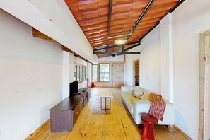 A modern interior with a wooden floor, a sofa, a TV, and a dining area. - Mtn-view Farmhouse w/ Pool in Atenas (San José)