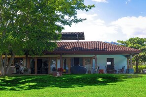 A house with a tiled roof, a covered porch, and a lawn. - Mtn-view Farmhouse w/ Pool in Atenas (San José)