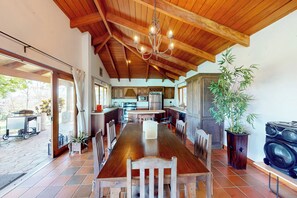 A spacious kitchen with wooden beams, a dining table with chairs, and a large potted plant. - Mtn-view Farmhouse w/ Pool in Atenas (San José)