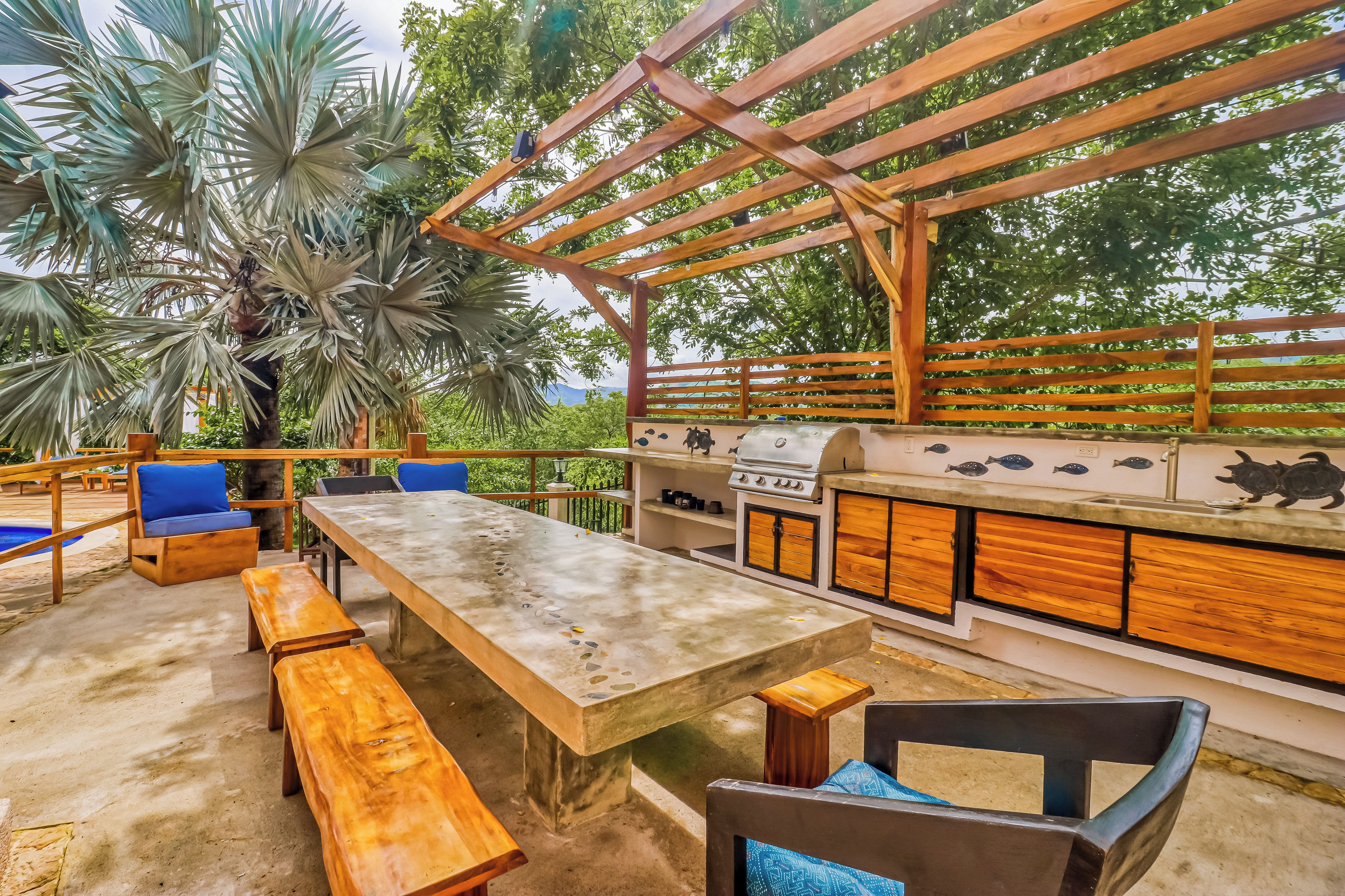 An outdoor patio with a wooden table, benches, and a grill.