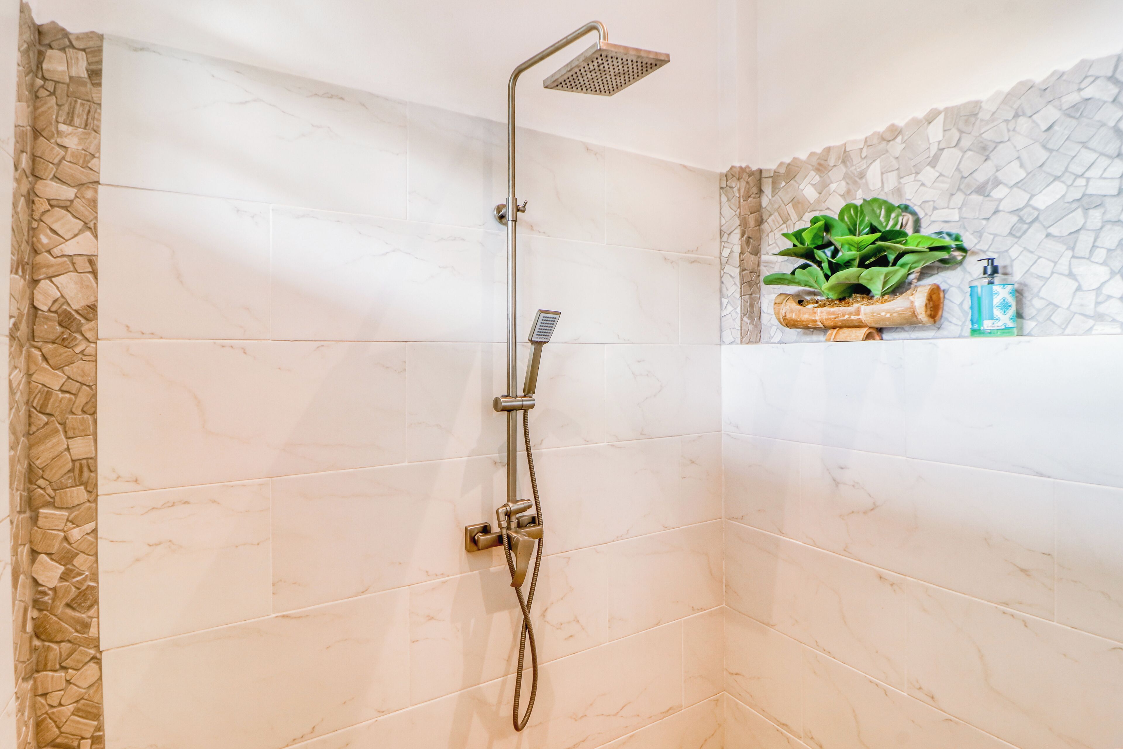 A shower with a handheld showerhead and a wall-mounted control.