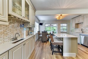 A kitchen with a dining area, wooden flooring, and a view of greenery outside. - Canal-front Gem w/ Dock & Guest Home in Cortez! (Cortez)
