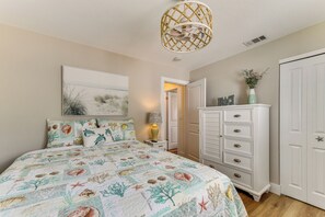 A bedroom with a bed, a dresser, a wall-mounted lamp, and a ceiling fan. - Canal-front Gem w/ Dock & Guest Home in Cortez! (Cortez)