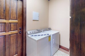 Un lavadero con lavadora y secadora, una puerta de madera y un interruptor de luz en la pared.