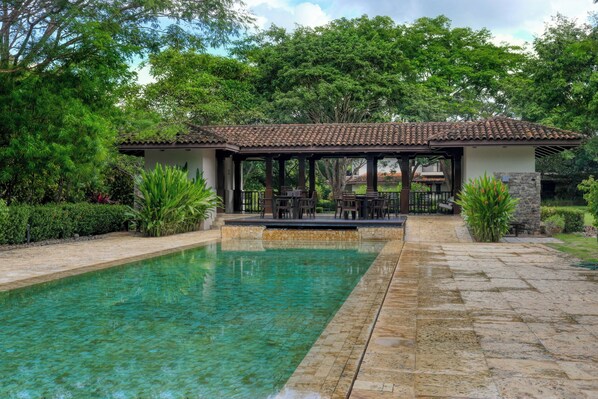 A pool with clear water, surrounded by a patio area with outdoor furniture.