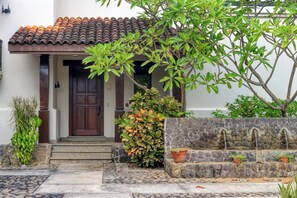 A traditional building with a tiled roof, a wooden door, and a stone wall with a water feature.