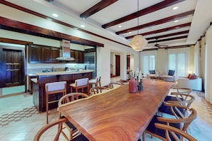 A spacious kitchen with a long wooden table, wooden chairs, and a modern island with a built-in oven.