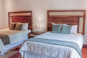 Une chambre d’hôtel avec deux lits, chacun doté d’une tête de lit en bois et d’une couvre-lit blanche.