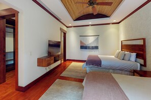Un dormitorio con cama, televisión, ventilador de techo y armario de madera.