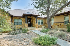 A stone house with a metal roof, a front porch, and a gravel driveway. - On 5+ Acres! Quiet Spring Branch Retreat w/ Views (Spring Branch)