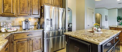 A kitchen with wooden cabinets, stainless steel appliances, granite countertops, and a central island.