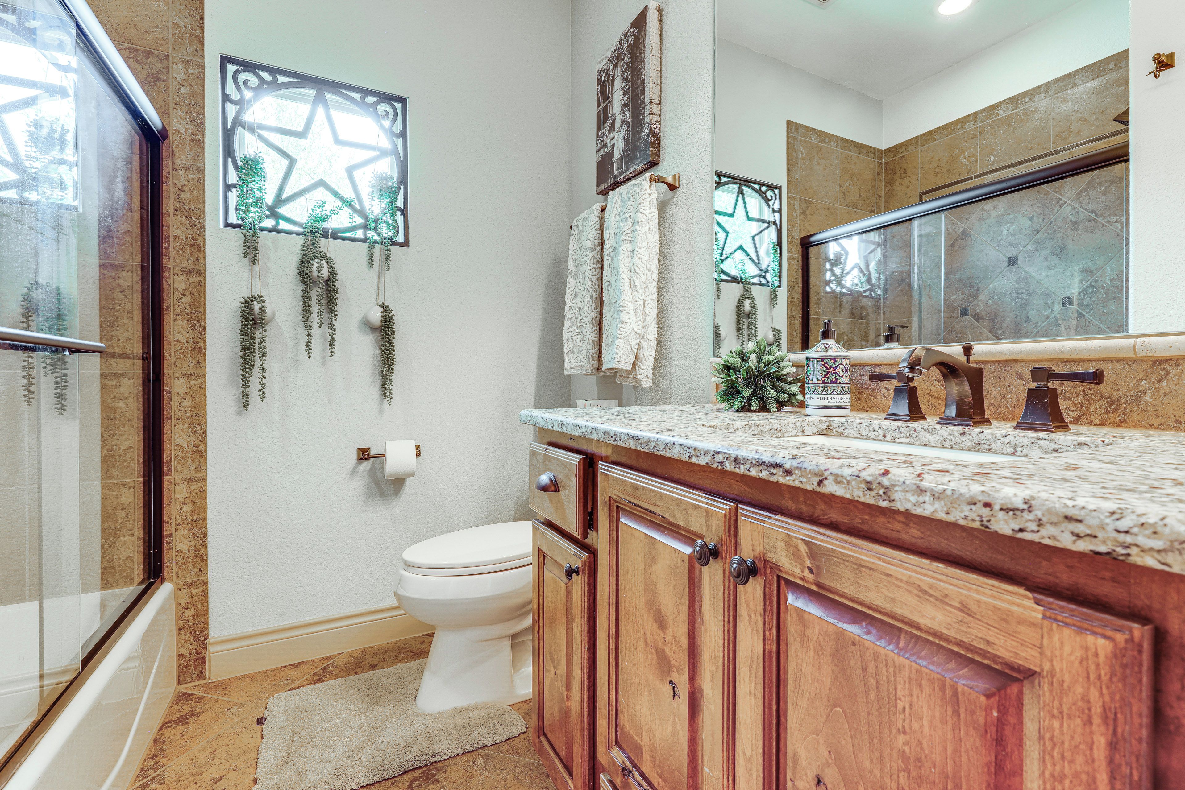 A bathroom with a toilet, wooden cabinets, a marble countertop, and a star-shaped decoration on the wall.