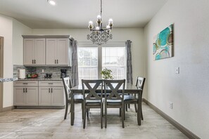 A modern kitchen with a dining area, featuring light-colored cabinetry, a chandelier, and a dining table with chairs. - Walk to Parks & Dining! Universal City Home (Universal City)