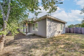 Einbungalow mit einer Veranda, einer kleinen angebauten Garage und einem eingezäunten Garten.