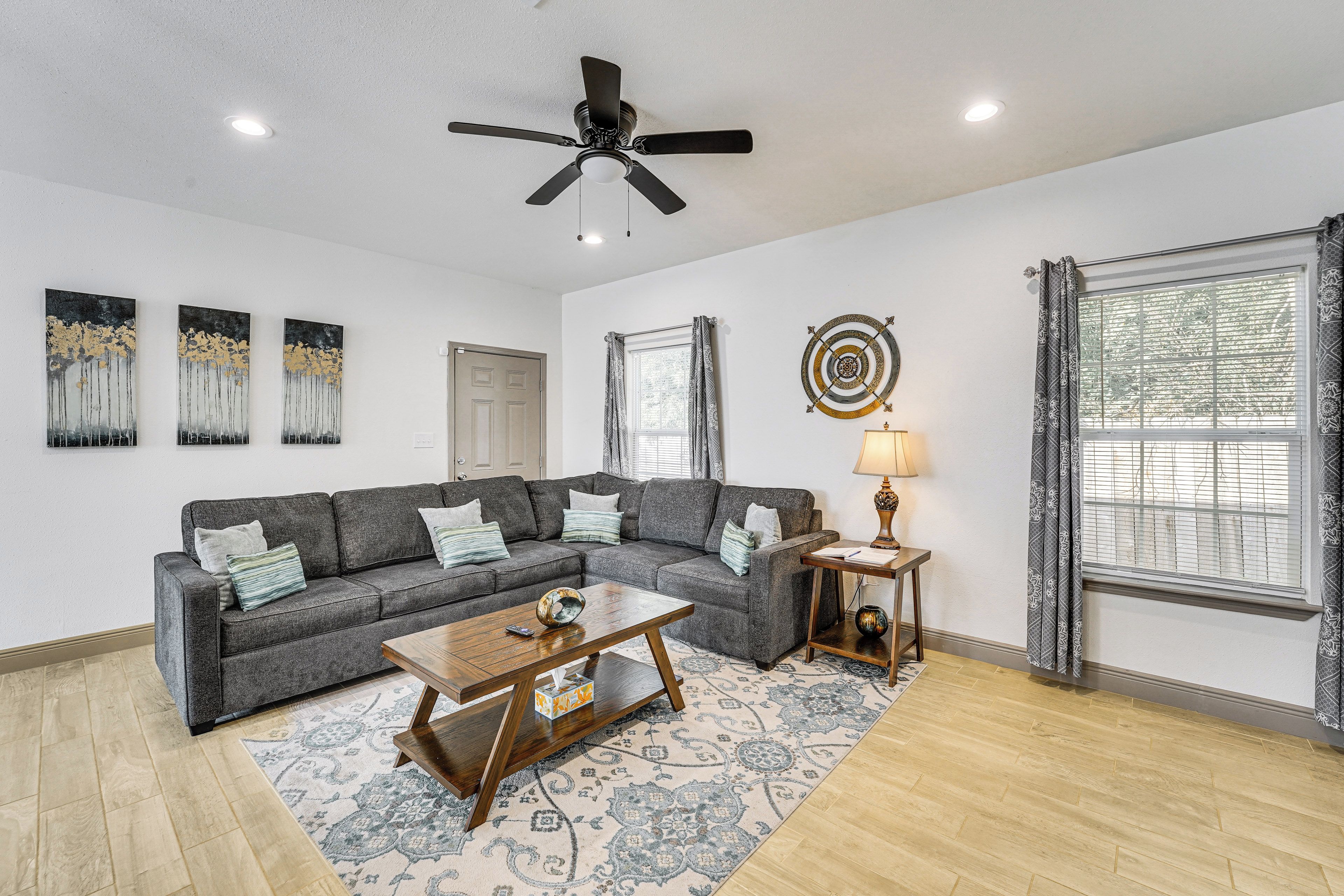 A living room with a gray sectional sofa, a coffee table, a floor lamp, and a ceiling fan.