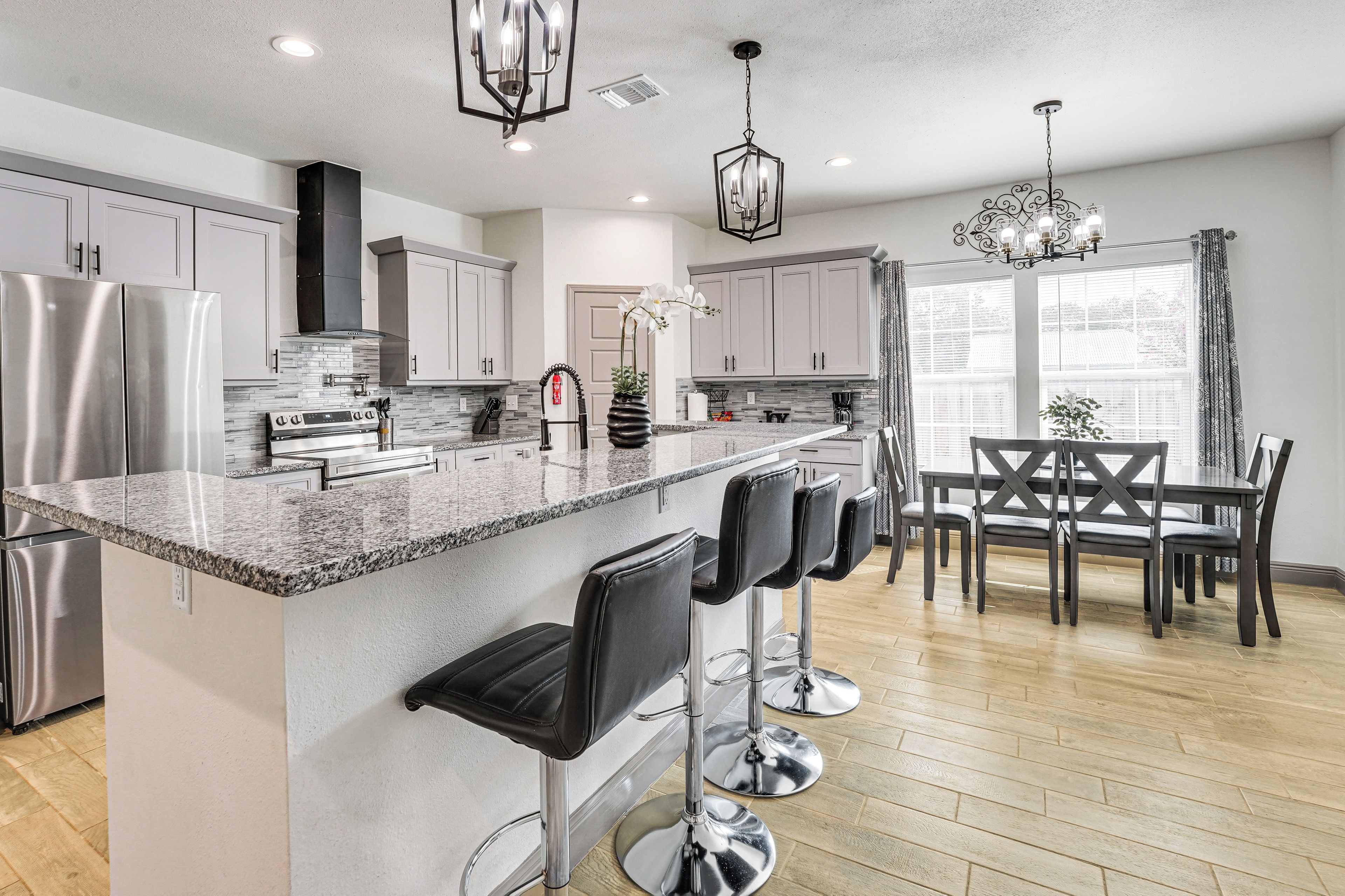A modern kitchen with stainless steel appliances, a granite countertop, and a bar area with stools.