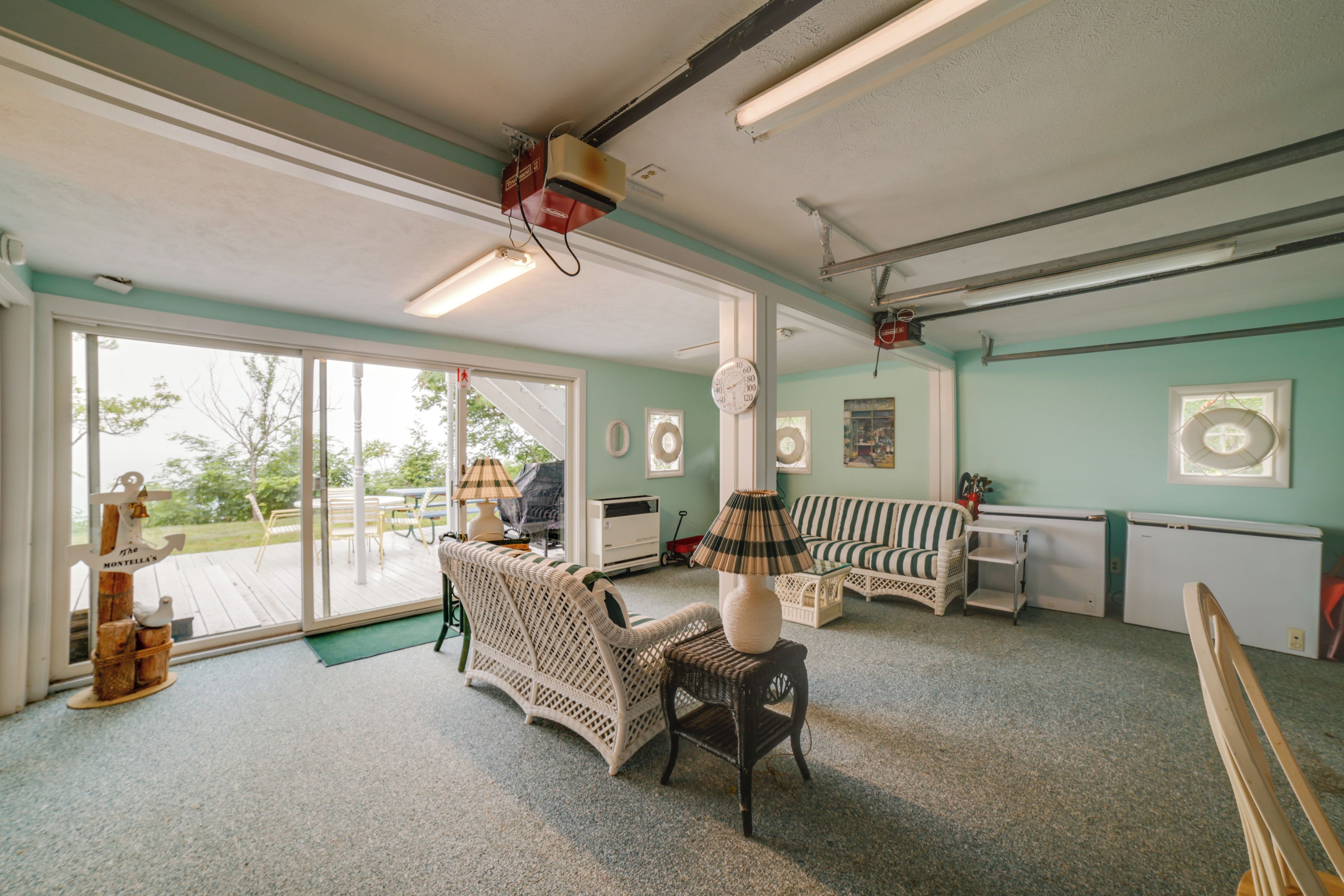 A spacious room with a large sliding glass door leading to an outdoor area, a ceiling fan, and a vintage-style lamp.