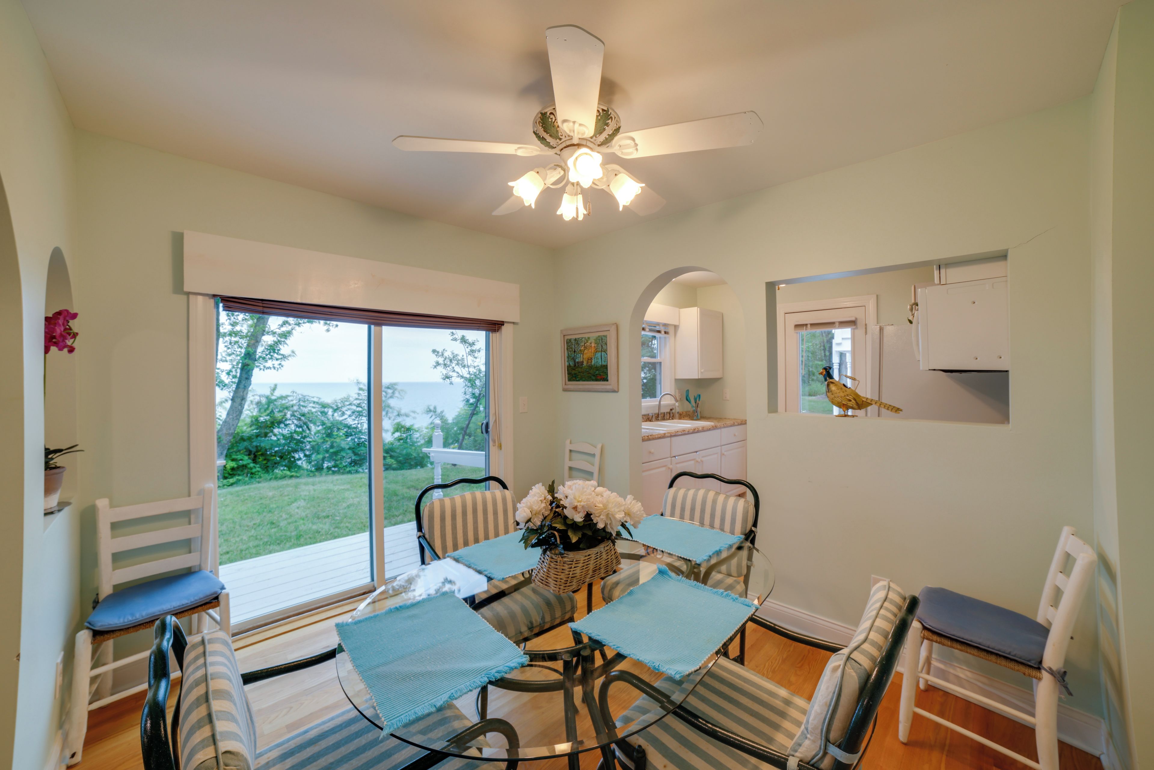 A dining area with a table, chairs, and a ceiling fan.