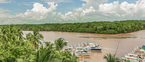 A riverfront with boats docked, surrounded by dense green foliage.