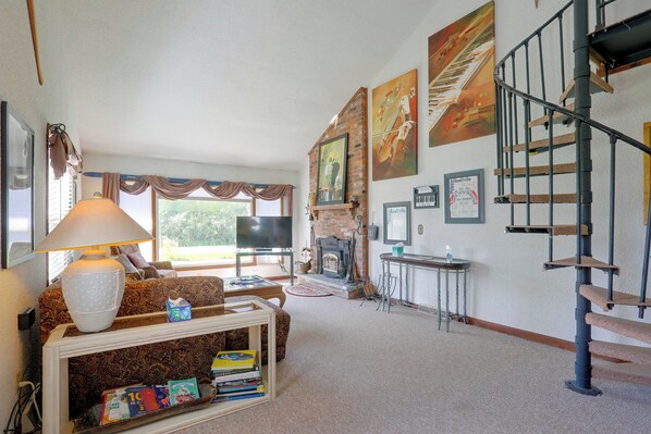 A living room with a fireplace, a TV, and a staircase.