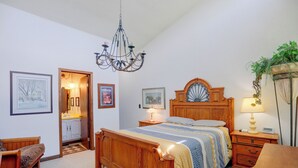 A bedroom with a wooden bed, a chandelier, a bedside table with a lamp, a nightstand, a chair, and a potted plant. - Carley House Too: Pet Friendly, Hot Tub, Fire Pit! (Ellicottville)