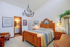A bedroom with a wooden bed, a chandelier, a bedside table with a lamp, a nightstand, a chair, and a potted plant. - Carley House Too: Pet Friendly, Hot Tub, Fire Pit! (Ellicottville)