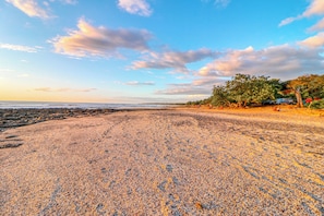 Una playa de guijarros con cielo despejado y horizonte lejano.