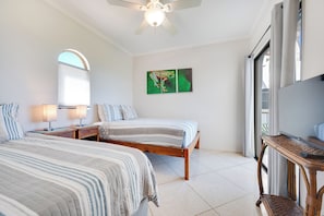 A bedroom with two beds, a ceiling fan, a TV, and a large window. - Walk to the Beach & Town! Tamarindo Condo (Tamarindo)