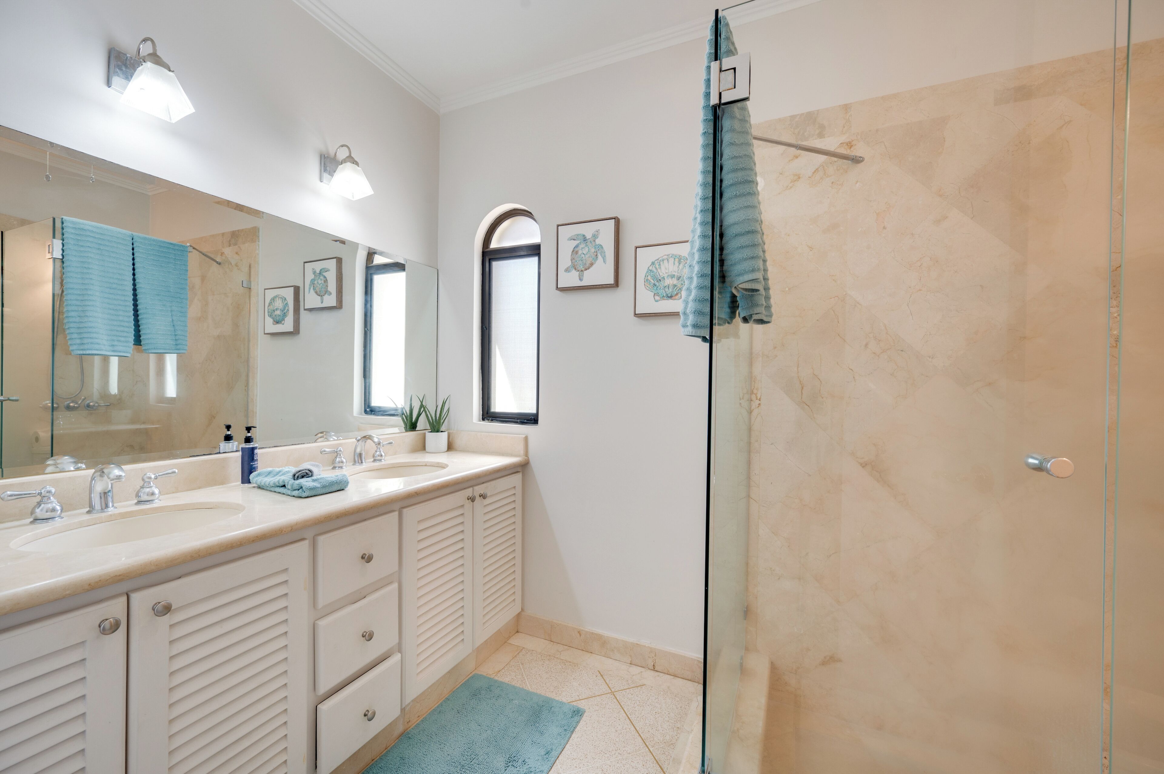 Une salle de bain avec une douche à parois de verre, un lavabo avec deux robinets et un miroir au-dessus du lavabo.
