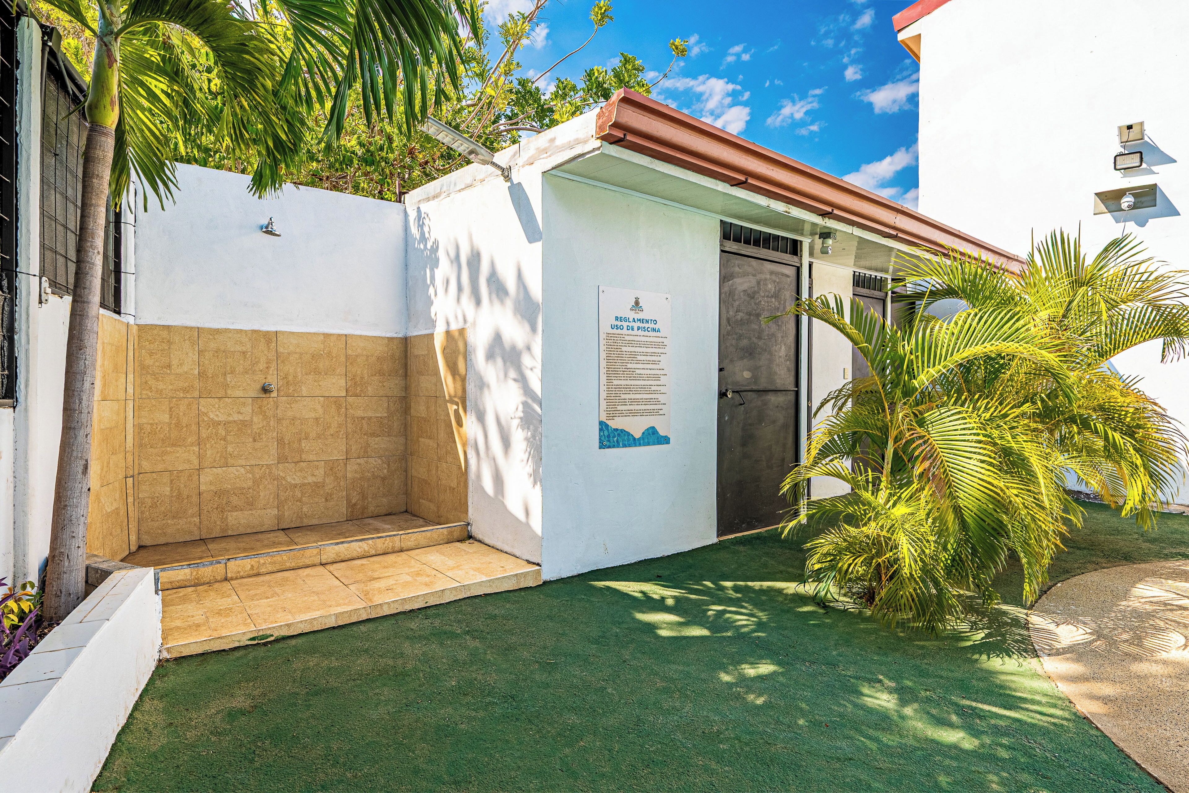 A small building with a door, a poster on the wall, and a palm tree in the foreground.