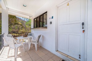 A covered outdoor seating area with a table and chairs, a white door with a number, and a window. - Playas del Coco Condo w/ Pool: Walk to Beach! (Sardinal)