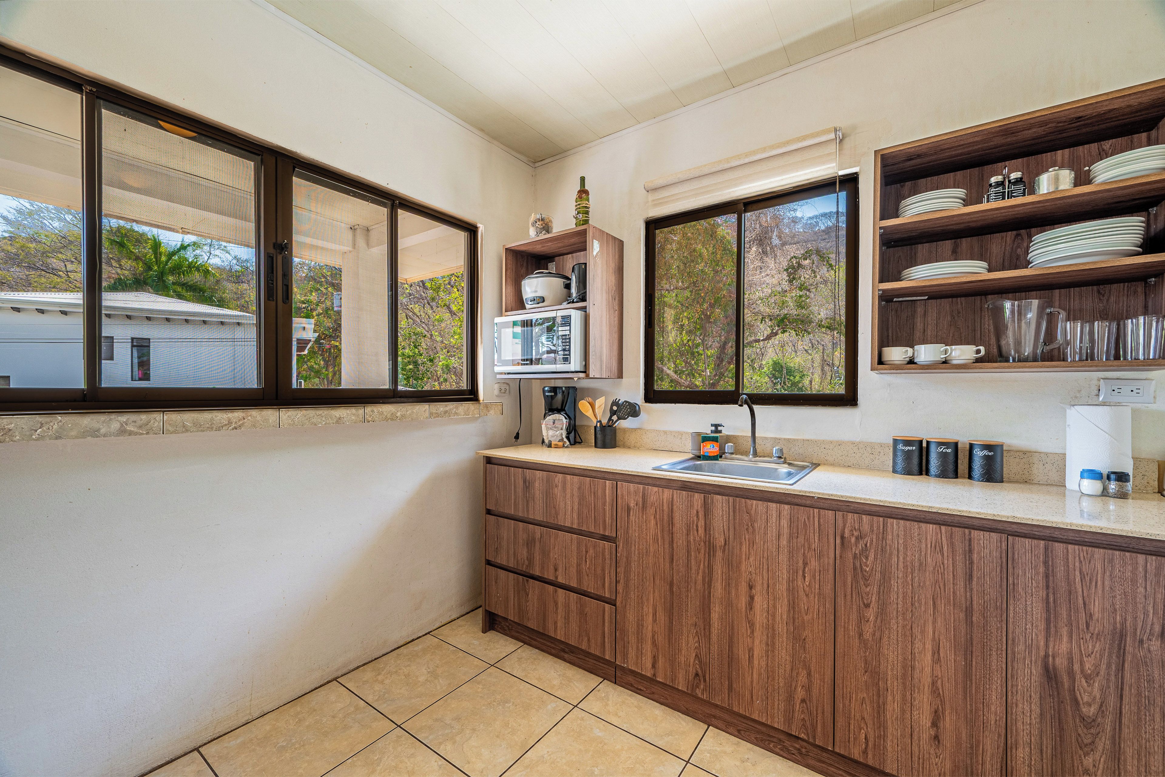 A kitchen with wooden cabinets, a countertop, a sink, and a window.
