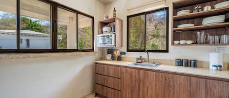 A kitchen with wooden cabinets, a countertop, a sink, and a window.