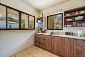A kitchen with wooden cabinets, a countertop, a sink, and a window. - Playas del Coco Condo w/ Pool: Walk to Beach! (Sardinal)