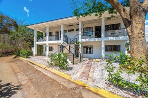 A two-story building with a balcony on the second floor, a staircase leading to the entrance, and a paved driveway. - Playas del Coco Condo w/ Pool: Walk to Beach! (Sardinal)