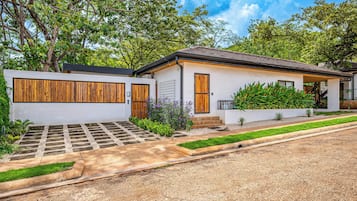 A modern two-story house with a white exterior, wooden doors, and a tiled roof.