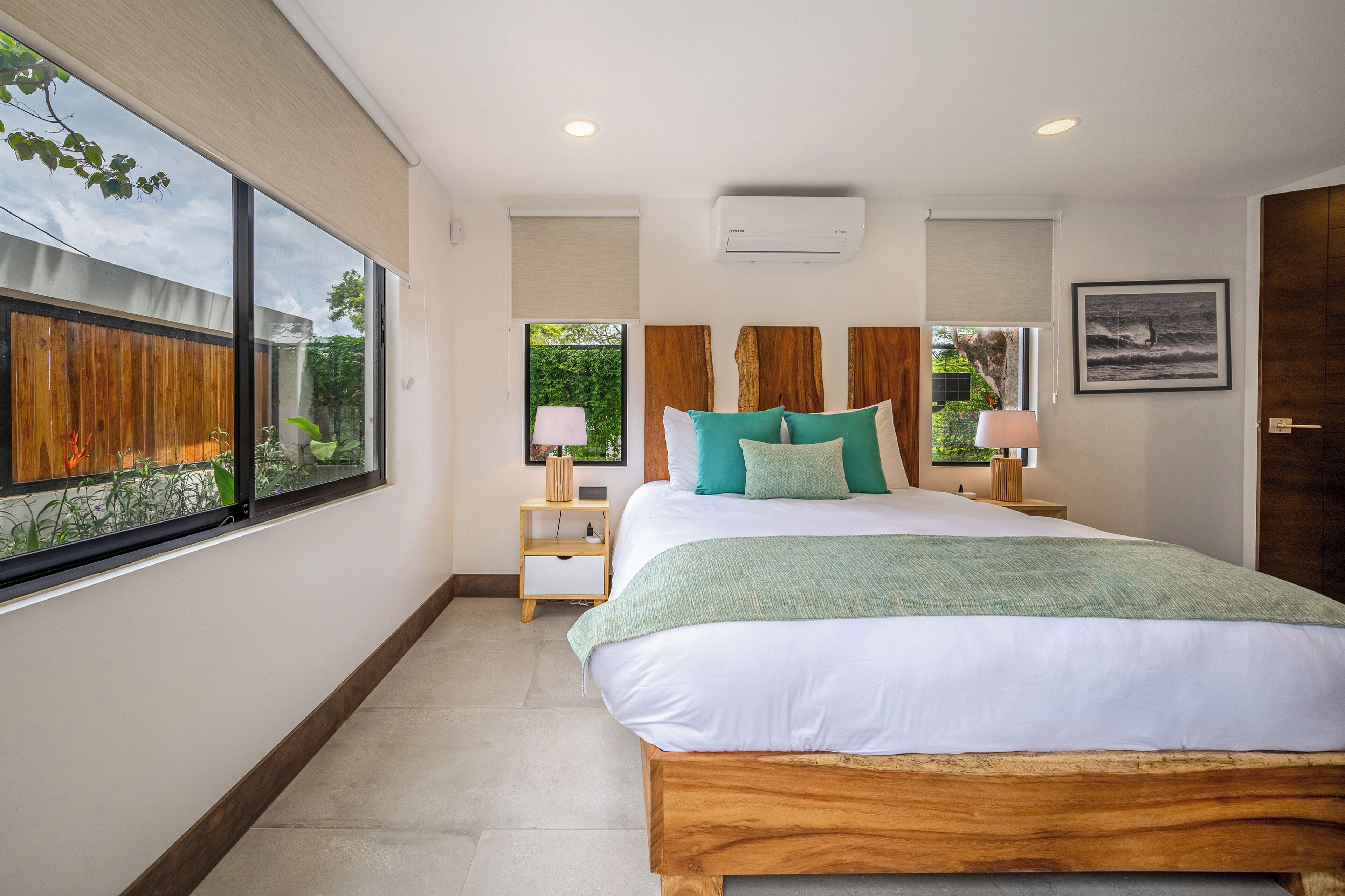 A bedroom with a large bed, a nightstand, a window, and a door.
