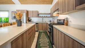 A modern kitchen with wooden cabinets, stainless steel appliances, and a central island. - Modern 4BR Family Home w/ Pool in Tamarindo (Tamarindo)