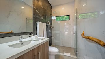 A modern bathroom with a marble vanity, a glass shower enclosure, and a mounted television.