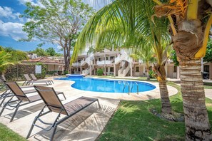 Ein Resort mit Swimmingpool, Liegestühlen und Palmen.