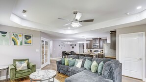 Uma sala de estar moderna com um sofá seccional, uma poltrona verde e uma mesa de centro de mármore.