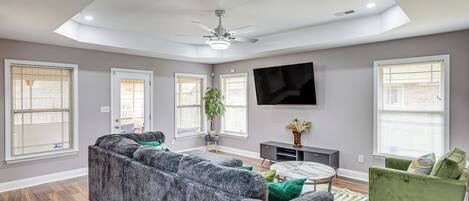 Una sala moderna con un sofá modular, una mesa de centro redonda y un televisor de pantalla plana montado en la pared.