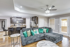 A modern living room with a sectional sofa, a marble coffee table, and a kitchen in the background.