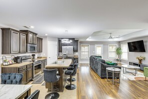 A modern kitchen with a central island, bar stools, and a dining area with a round table.