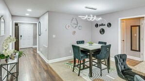 Uma sala de jantar com mesa de mármore e cadeiras estofadas, luminária decorativa no teto e espelhos fixados na parede.