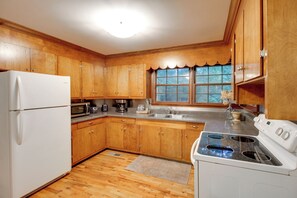 A kitchen with wooden cabinets, a refrigerator, a microwave, a coffee maker, and a stove. - Basecamp in Skyline, 10 Mi to Walls of Jericho (Scottsboro)