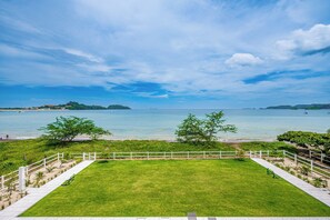 A grassy lawn with a white fence, a clear view of the sea, and distant islands. - Oceanfront Escape in Playa Potrero, Costa Rica (Tempate)