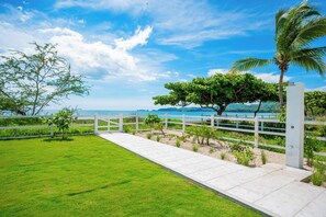 A coastal pathway with a white fence, lush green grass, and a view of the sea. - Oceanfront Escape in Playa Potrero, Costa Rica (Tempate)