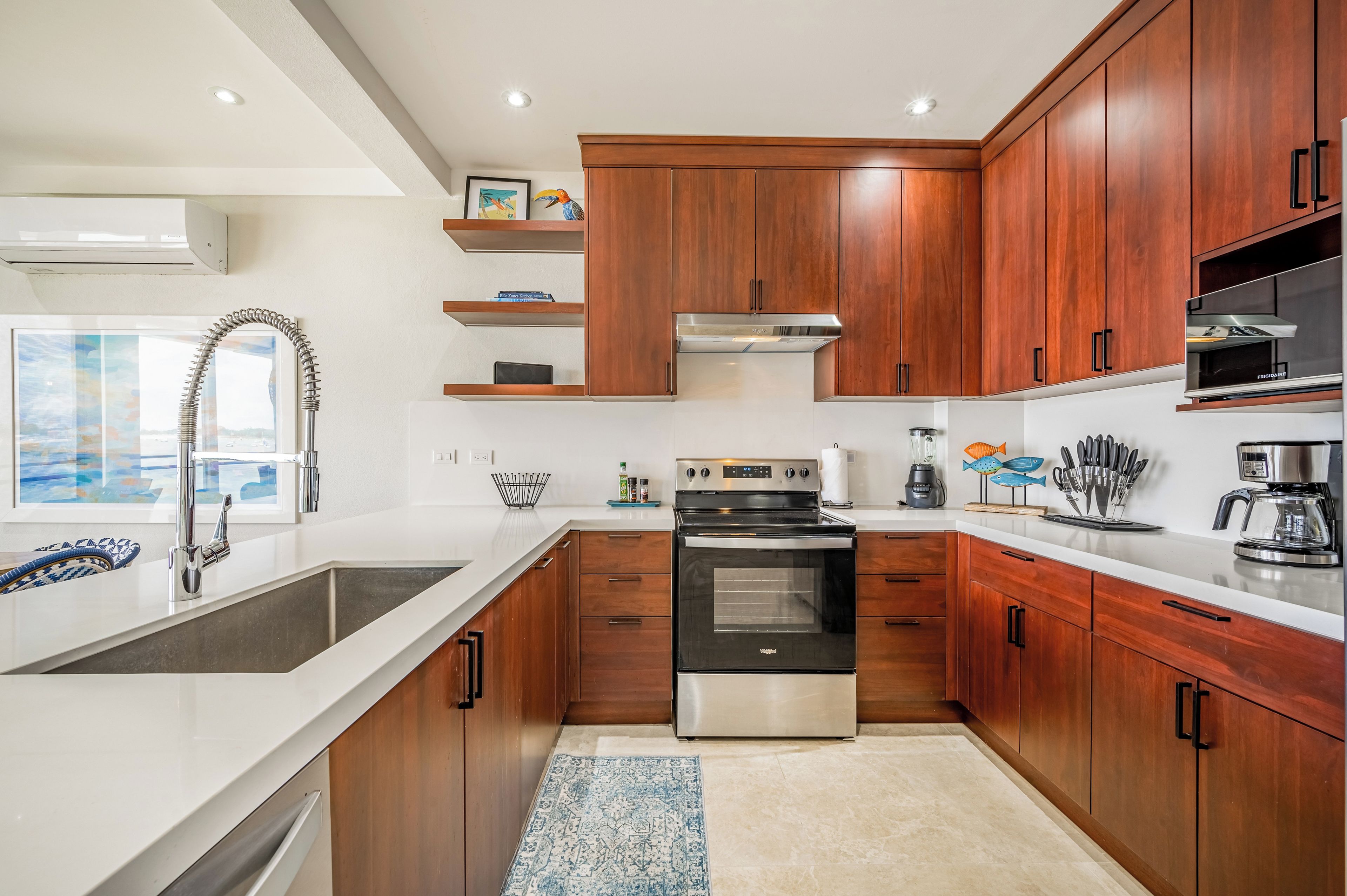 Une cuisine moderne avec des meubles en bois, un four en acier inoxydable et un plan de travail blanc.