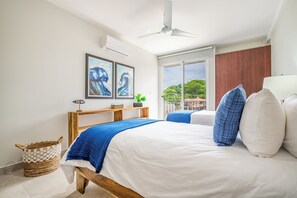 A bedroom with a bed, a ceiling fan, a window with a view, and artwork on the wall. - Oceanfront Escape in Playa Potrero, Costa Rica (Tempate)